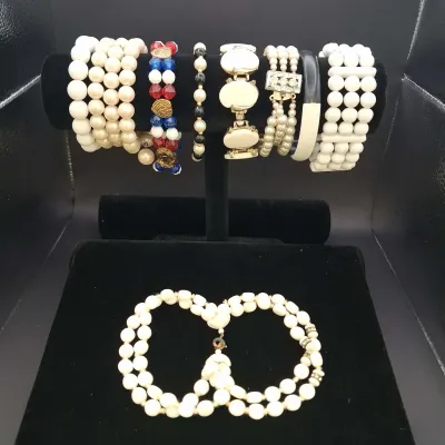Sale Photo Thumbnail #128: Assorted costume jewelry lot featuring white bead and faux pearl stretch bracelets, a patriotic red, white and blue beaded bracelet, gold-tone fashion bracelets with faux pearls and rhinestones, a black-and-white bangle, and a coordinating white beaded ne