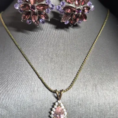 Sale Photo Thumbnail #208: Beautiful 1.5 carat Amethyst gold tone Necklace & Amethyst Rhinestone Earrings
> herringbone chain necklace....12"long
> Amethyst pendant .75" dangle
> Amethyst earring are clip style.