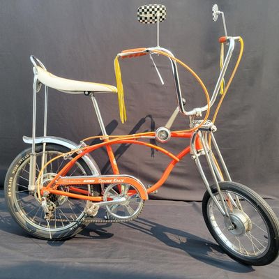 Sale Photo Thumbnail #5: Schwinn Sting-Ray Orange Krate with 5-speed Stik-Shift, springer front fork, high-rise handlebars, orange glitter grips, tall sissy bar, 1990's reproduction schwinn krate banana seat, original white letter slik rear tire, rear reflector, a PAIR of Schwinn