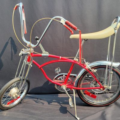 Sale Photo Thumbnail #39: Red Schwinn Sting-Ray Apple Krate with 5-speed Stik-Shift, springer front end, high-rise bars, red grips, tall sissy bar, striped banana seat, front drum-style hub and rear redline slik tire. Complete, well-presented example with normal vintage wear inclu