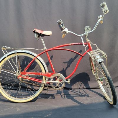Sale Photo Thumbnail #96: Red Schwinn Corvette loaded with period-style accessories including whitewall tires, full chrome fenders, front and rear carriers, chrome tank insert, red Mesinger-style saddle, bell, headlight, twin front reflectors and cyclometer/control accessories. Ve
