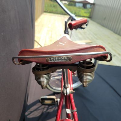 Sale Photo Thumbnail #119: Red Schwinn Jaguar with whitewall tires, full fenders, rear carrier, tank-style frame insert, red Mesinger-style saddle, bell, front light equipment and Jaguar-marked chainguard. The rear wheel sports a Bendix Red Band 2 speed Automatic Hub.  A nicely equ
