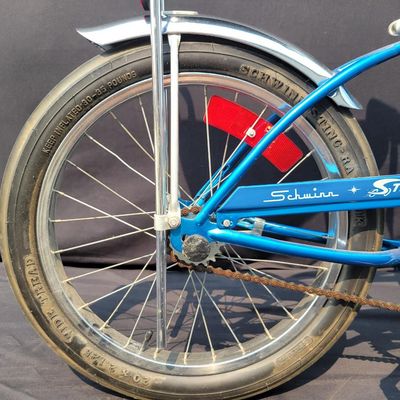 Sale Photo Thumbnail #169: Blue Schwinn Sting-Ray with banana saddle, tall sissy bar, high-rise handlebars, blue grips, chrome rear fender/reflector. Classic muscle-bike styling in good vintage condition with expected wear to the seat, grips, paint and chrome. Major components are 