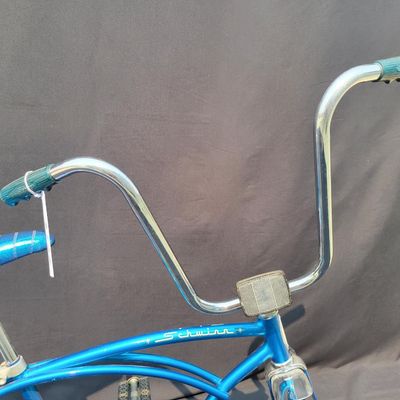 Sale Photo Thumbnail #170: Blue Schwinn Sting-Ray with banana saddle, tall sissy bar, high-rise handlebars, blue grips, chrome rear fender/reflector. Classic muscle-bike styling in good vintage condition with expected wear to the seat, grips, paint and chrome. Major components are 