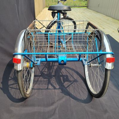Sale Photo Thumbnail #206: Blue Schwinn Town & Country adult tricycle with step-through frame, large rear wire cargo basket, Town & Country chainguard, fenders, reflectors and black replacement saddle. Complete and useful vintage trike showing surface rust, basket corrosion, drivet