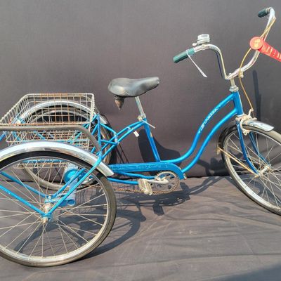 Sale Photo Thumbnail #202: Blue Schwinn Town & Country adult tricycle with step-through frame, large rear wire cargo basket, Town & Country chainguard, fenders, reflectors and black replacement saddle. Complete and useful vintage trike showing surface rust, basket corrosion, drivet