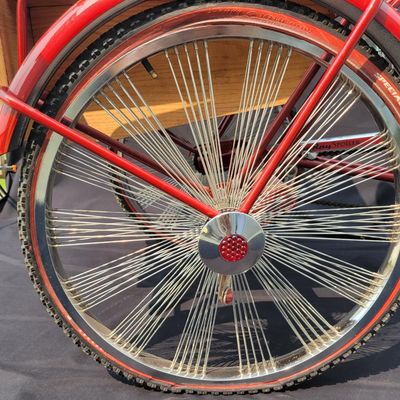 Sale Photo Thumbnail #212: Custom red 3-speed cargo tricycle with long wood-slatted rear cargo bed, tall handlebars, flame-style saddle, headlight, flags and assorted bottle/cargo accessories. Chainguard is marked “Ray Spoiler / 3 Speed.” A fun one-off custom build with strong 