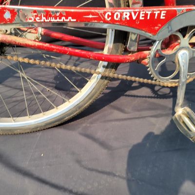 Sale Photo Thumbnail #229: Red Schwinn Corvette with chrome fenders, whitewall tires, brown saddle and Corvette chainguard. Complete vintage middleweight showing heavier cosmetic wear including faded/scratched graphics, paint chips and chrome oxidation. Good restoration candidate w