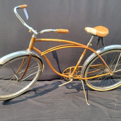 Sale Photo Thumbnail #243: Coppertone Schwinn Tiger with Tiger-marked chainguard, full fenders, brown saddle and bell. Classic mid-1960s Schwinn middleweight styling with good completeness and an attractive survivor look. Shows paint/chrome patina, saddle marks, aged tires and ligh