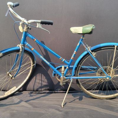 Sale Photo Thumbnail #259: Blue Schwinn Racer women's 3-speed with step-through frame, full fenders, chainguard and green/cream saddle. Complete vintage commuter showing surface rust, paint wear, chrome oxidation and age to the saddle and tires. A good rider-restoration project wit