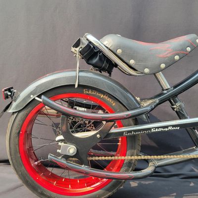 Sale Photo Thumbnail #278: Large adult-size Schwinn Sting-Ray Spoiler chopper with long springer/girder-style front end, black frame with red flame graphics, red wheels, fat rear tire, flame saddle, mirrors and headlamp-style accessories. Much larger and scarcer than the common you