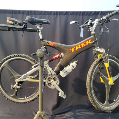 Sale Photo Thumbnail #296: 1996 Trek Y33 OCLV carbon full-suspension mountain bike with distinctive carbon Y-frame, yellow suspension linkage/fork, rear shock, multi-speed drivetrain and premium Spinergy composite tri-spoke wheels. Includes water bottle, mirror and rear rack/bag. A