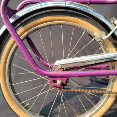 Sale Photo Thumbnail #300: Purple/magenta Bianchi folding bicycle with 20-inch wheels, center folding hinge, Bianchi graphics, chrome fenders, rear rack, tan-sidewall tires, high handlebars and twin front light/reflector accessories. Distinctive and substantially complete with grea