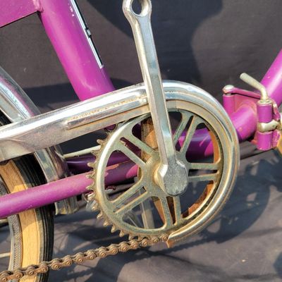Sale Photo Thumbnail #299: Purple/magenta Bianchi folding bicycle with 20-inch wheels, center folding hinge, Bianchi graphics, chrome fenders, rear rack, tan-sidewall tires, high handlebars and twin front light/reflector accessories. Distinctive and substantially complete with grea