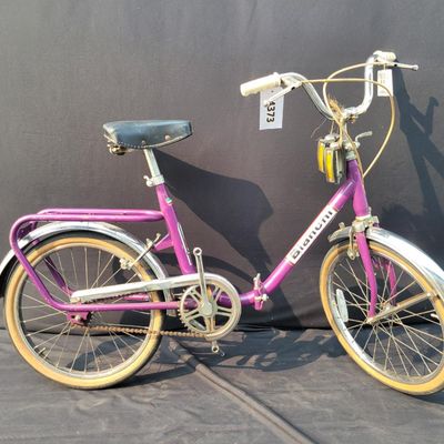 Sale Photo Thumbnail #297: Purple/magenta Bianchi folding bicycle with 20-inch wheels, center folding hinge, Bianchi graphics, chrome fenders, rear rack, tan-sidewall tires, high handlebars and twin front light/reflector accessories. Distinctive and substantially complete with grea