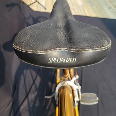 Sale Photo Thumbnail #308: Orange/gold Triumph women's step-through bicycle with full fenders, chainguard, white grips, kickstand and black Specialized replacement saddle. Attractive vintage utility bike with normal paint wear and age. One tire is visibly aged/cracked or low and wi