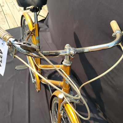 Sale Photo Thumbnail #306: Orange/gold Triumph women's step-through bicycle with full fenders, chainguard, white grips, kickstand and black Specialized replacement saddle. Attractive vintage utility bike with normal paint wear and age. One tire is visibly aged/cracked or low and wi