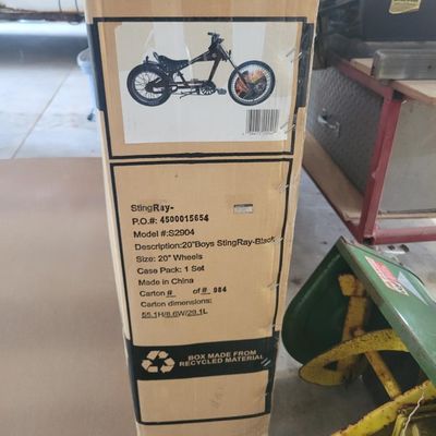 Sale Photo Thumbnail #323: Boxed black Schwinn Sting-Ray chopper, model S2904, from the early-2000s Pacific Cycle era. Factory carton identifies a 20-inch boys Sting-Ray in black. Bicycle remains boxed/unassembled with normal shelf and handling wear to the carton. Contents have not