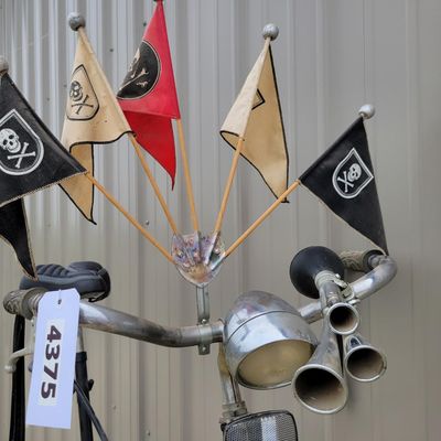 Sale Photo Thumbnail #335: One-of-a-kind custom tallbike built from stacked/welded bicycle frames and finished primarily in black. Fitted with multi-speed rear derailleur, front hand brake, high seating position and a full assortment of skull/pirate decorations, flags, tassels and 