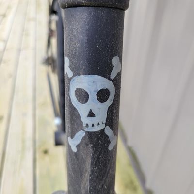 Sale Photo Thumbnail #334: One-of-a-kind custom tallbike built from stacked/welded bicycle frames and finished primarily in black. Fitted with multi-speed rear derailleur, front hand brake, high seating position and a full assortment of skull/pirate decorations, flags, tassels and 