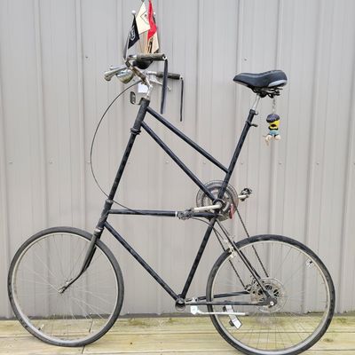 Sale Photo Thumbnail #337: One-of-a-kind custom tallbike built from stacked/welded bicycle frames and finished primarily in black. Fitted with multi-speed rear derailleur, front hand brake, high seating position and a full assortment of skull/pirate decorations, flags, tassels and 