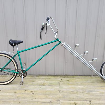 Sale Photo Thumbnail #346: Custom green extended-fork chopper/cruiser with an extremely long twin-tube front fork, small front wheel, whitewall rear tire, tall ape-hanger bars, Stream Ride sprung saddle, chrome rear rack, tassels, bell and multiple bullet-style mirror/reflector acc