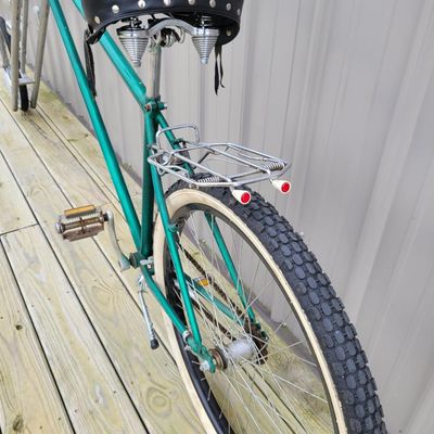 Sale Photo Thumbnail #339: Custom green extended-fork chopper/cruiser with an extremely long twin-tube front fork, small front wheel, whitewall rear tire, tall ape-hanger bars, Stream Ride sprung saddle, chrome rear rack, tassels, bell and multiple bullet-style mirror/reflector acc