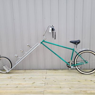 Sale Photo Thumbnail #338: Custom green extended-fork chopper/cruiser with an extremely long twin-tube front fork, small front wheel, whitewall rear tire, tall ape-hanger bars, Stream Ride sprung saddle, chrome rear rack, tassels, bell and multiple bullet-style mirror/reflector acc