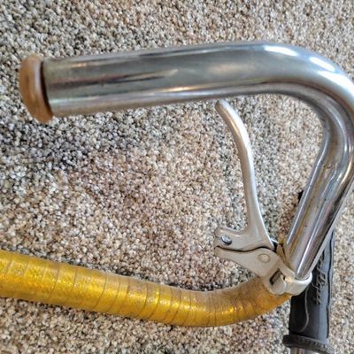 Sale Photo Thumbnail #350: Lot of two vintage bicycle handlebar assemblies: one chrome high-rise/ape-hanger bar with black Schwinn grips, plus one chrome set possibly from a Sears Screamer  with stem, dual brake levers and aged gold/yellow wrap. Both show typical use, scratches, ch