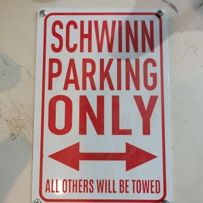 Sale Photo Thumbnail #380: Custom Schwinn-themed display featuring six vintage-style Schwinn “S” saddle tops arranged around a round white base with a red-and-white “SCHWINN PARKING ONLY – ALL OTHERS WILL BE TOWED” center sign. Seat colors include red, teal, yellow, black