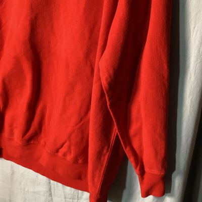 Sale Photo Thumbnail #14: Red long-sleeve crewneck sweatshirt featuring a center front embroidered and embellished reindeer applique with holiday light details. Measures approximately 28 to 29 inches in length as shown against the tape measure. Pre-owned condition with light signs