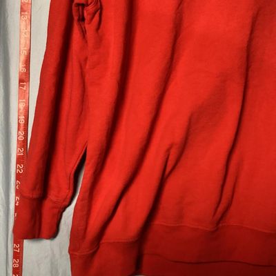 Sale Photo Thumbnail #15: Red long-sleeve crewneck sweatshirt featuring a center front embroidered and embellished reindeer applique with holiday light details. Measures approximately 28 to 29 inches in length as shown against the tape measure. Pre-owned condition with light signs
