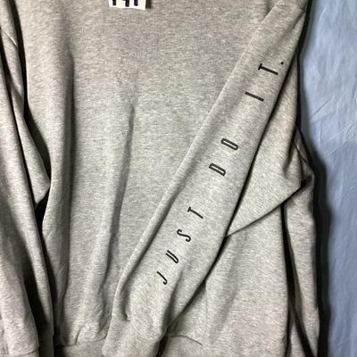 Sale Photo Thumbnail #86: Grey Nike Dri-FIT crewneck sweatshirt featuring 'JUST DO IT.' printed along the left sleeve and a small black Nike swoosh on the upper back. Tagged size XL (Extra Large). Shows light overall wear consistent with normal use, with no major stains or holes v