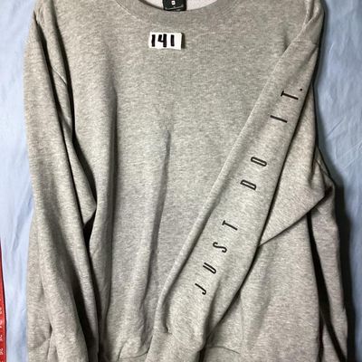Sale Photo Thumbnail #84: Grey Nike Dri-FIT crewneck sweatshirt featuring 'JUST DO IT.' printed along the left sleeve and a small black Nike swoosh on the upper back. Tagged size XL (Extra Large). Shows light overall wear consistent with normal use, with no major stains or holes v