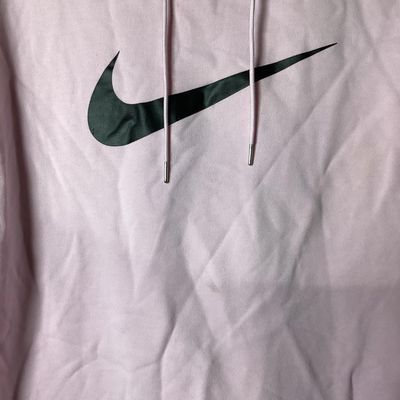 Sale Photo Thumbnail #89: Light pink long-sleeve hoodie by Nike featuring a prominent black graphic Swoosh logo on the front chest, drawstring hood, and ribbed cuffs and hem. Pre-owned condition with light fabric creasing and faint surface marks visible upon close inspection. Leng