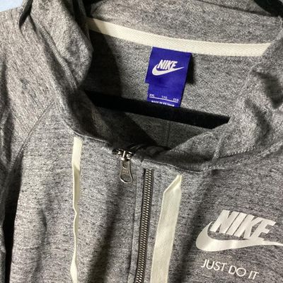 Sale Photo Thumbnail #112: Nike heather gray full-zip hooded sweatshirt featuring white 'Nike Just Do It' logo on the chest. Has front hand pockets, drawstring hood, and raglan sleeves. Tag size XXL (1XG/2EG). Lightly worn in good pre-owned condition with no major stains, rips, or 
