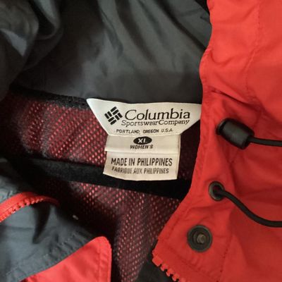 Sale Photo Thumbnail #126: Red and dark gray Columbia Sportswear Company hooded windbreaker/rain jacket. Features full zip front with snap closure overlay, mesh lining, hood with drawstring, and side pockets. Women's size XL, made in Philippines. Light wear visible, overall good pr