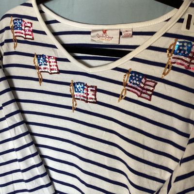 Sale Photo Thumbnail #132: Women's Quacker Factory by Jeanne Bice v-neck top featuring navy blue and white horizontal stripes with sequined American flag embellishments across the chest and shoulders. 3/4 length sleeves. Size XL. Made in China. In good pre-owned condition with no v