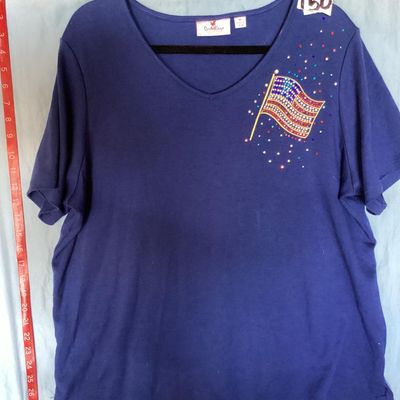 Sale Photo Thumbnail #135: Quacker Factory short sleeve V-neck top in blue, featuring a embellished American flag design on the chest with colorful rhinestones and studs. Tagged size XL. Made in China. Measures approximately 28 inches in length from shoulder to hem. Good pre-owned 