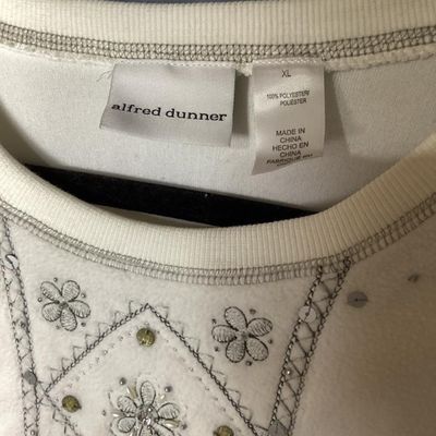 Sale Photo Thumbnail #148: An Alfred Dunner long-sleeve fleece sweatshirt in cream/white, featuring intricate floral embroidery, sequins, and bead accents along the front panel. Made from 100% polyester. Size XL. Appears to be in good pre-owned condition with minor signs of wear.