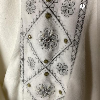 Sale Photo Thumbnail #150: An Alfred Dunner long-sleeve fleece sweatshirt in cream/white, featuring intricate floral embroidery, sequins, and bead accents along the front panel. Made from 100% polyester. Size XL. Appears to be in good pre-owned condition with minor signs of wear.