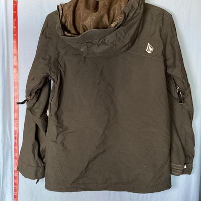 Sale Photo Thumbnail #175: Volcom hooded jacket in dark brown with bright orange and yellow patterned interior lining. Features zip-up and hook-and-loop closures, multiple cargo and zipper pockets, powder skirt, and underarm zip vents. Marked size Youth Large (L). Overall good pre-