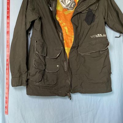 Sale Photo Thumbnail #172: Volcom hooded jacket in dark brown with bright orange and yellow patterned interior lining. Features zip-up and hook-and-loop closures, multiple cargo and zipper pockets, powder skirt, and underarm zip vents. Marked size Youth Large (L). Overall good pre-