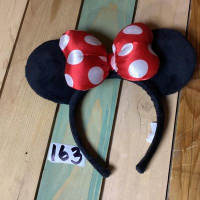 Sale Photo Thumbnail #217: Minnie Mouse themed headband featuring black plush mouse ears and a red bow with white polka dots. Fabric-wrapped headband. Measures approximately 10 inches wide by 8 inches tall. In good pre-owned condition with intact tag.