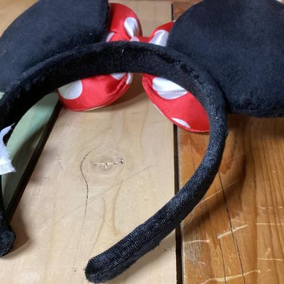 Sale Photo Thumbnail #221: Minnie Mouse themed headband featuring black plush mouse ears and a red bow with white polka dots. Fabric-wrapped headband. Measures approximately 10 inches wide by 8 inches tall. In good pre-owned condition with intact tag.