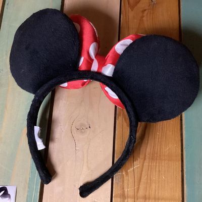 Sale Photo Thumbnail #219: Minnie Mouse themed headband featuring black plush mouse ears and a red bow with white polka dots. Fabric-wrapped headband. Measures approximately 10 inches wide by 8 inches tall. In good pre-owned condition with intact tag.