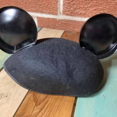 Sale Photo Thumbnail #224: Black felt Mickey Mouse ear hat featuring a front Walt Disney World patch with Mickey Mouse graphics. The interior lining is decorated with printed Mickey Mouse Club graphics. Comes with an elastic chin strap. Pre-owned condition with minor surface dust/f
