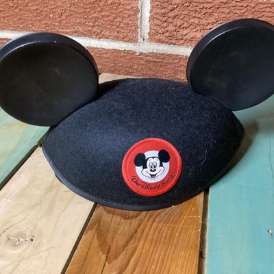Sale Photo Thumbnail #222: Black felt Mickey Mouse ear hat featuring a front Walt Disney World patch with Mickey Mouse graphics. The interior lining is decorated with printed Mickey Mouse Club graphics. Comes with an elastic chin strap. Pre-owned condition with minor surface dust/f