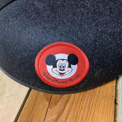 Sale Photo Thumbnail #223: Black felt Mickey Mouse ear hat featuring a front Walt Disney World patch with Mickey Mouse graphics. The interior lining is decorated with printed Mickey Mouse Club graphics. Comes with an elastic chin strap. Pre-owned condition with minor surface dust/f