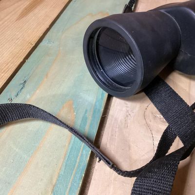 Sale Photo Thumbnail #251: Pair of Bushnell 10x-30x50 zoom binoculars featuring variable magnification controls and a attached black woven neck strap. The casing is finished in a durable black rubberized coating. In used condition with light surface dust and minor wear consistent w